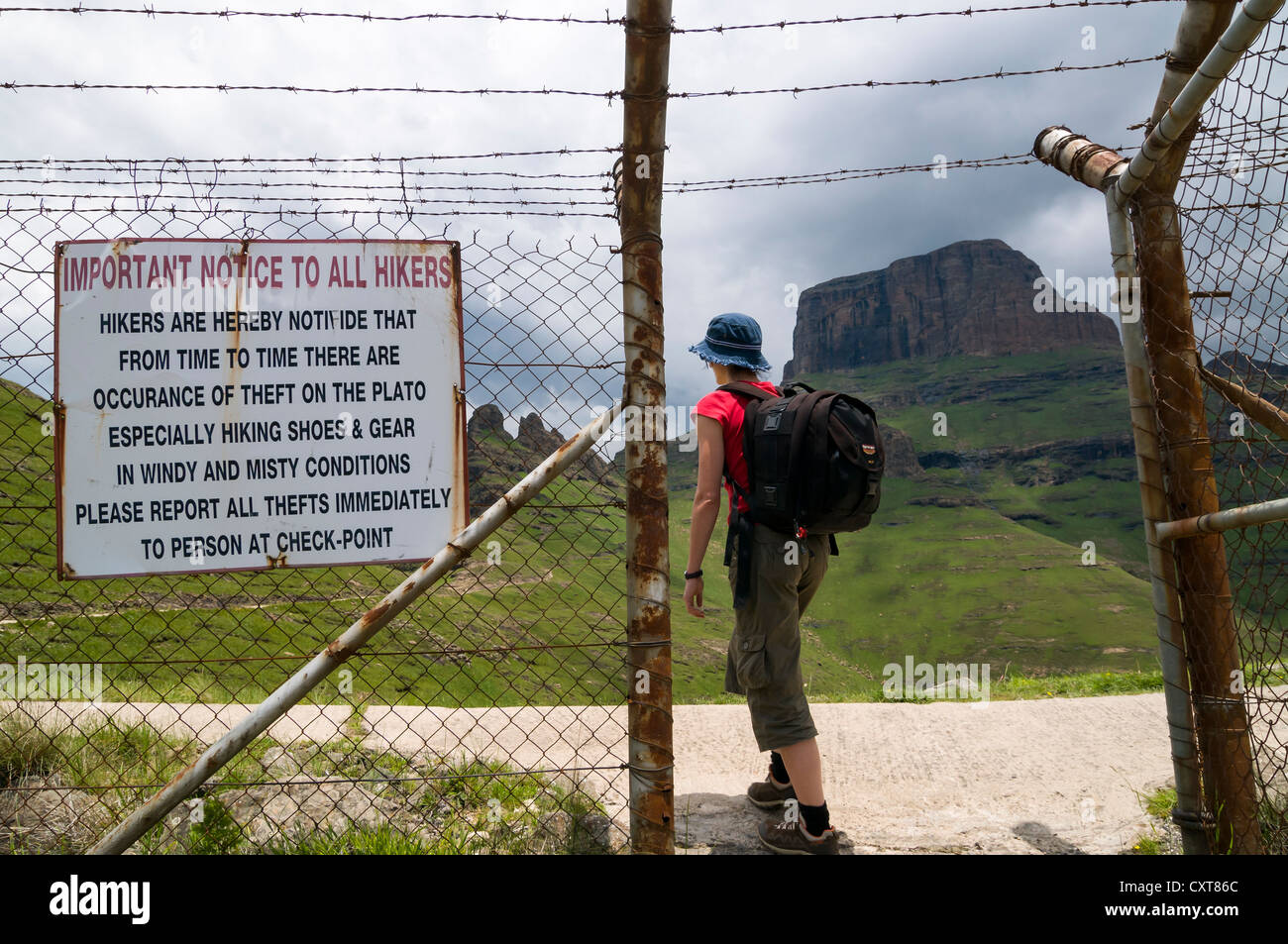 Warnign sign 'beware of thefts', woman at the entrance to the Sentinel Hiking Trail, Drakensberg Mountains, KwaZulu-Natal Stock Photo