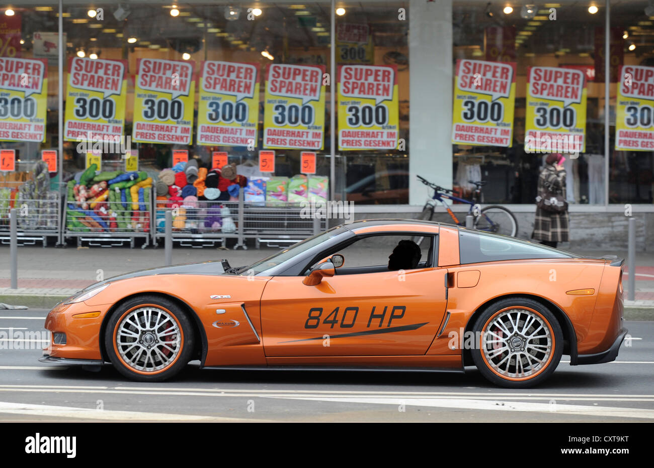 Flashy car, driver's face made unrecognisable, parked in front of a cheap discount store in Oberbilker Markt square, Duesseldorf Stock Photo