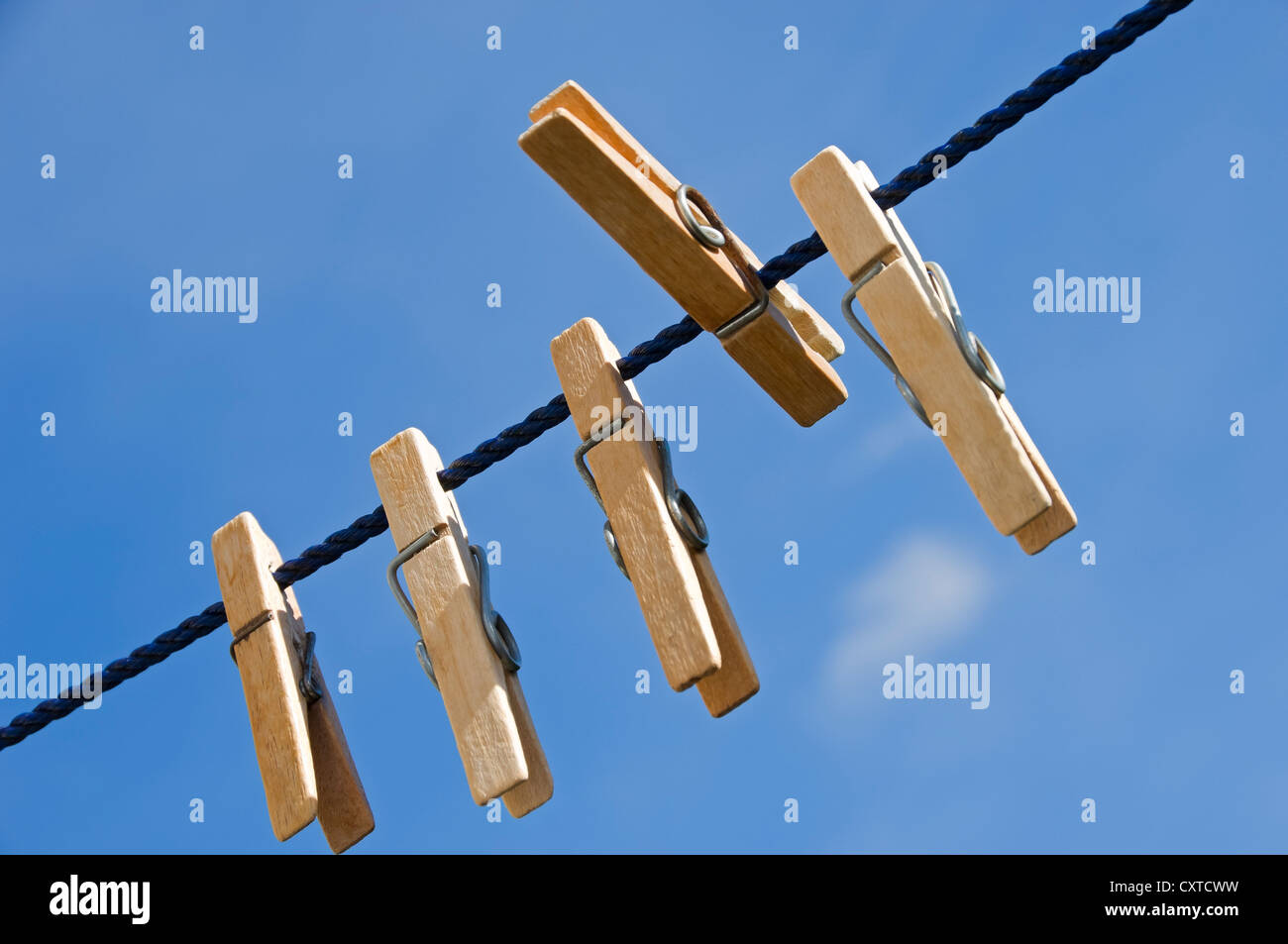Close up of wooden clothes pegs peg on washing line with blue sky background England UK United Kingdom GB Great Britain Stock Photo
