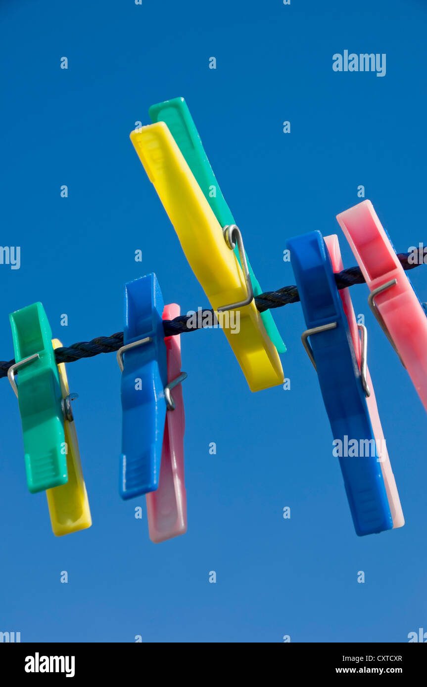 Close up of plastic clothes pegs peg on washing line with blue sky background England UK United Kingdom GB Great Britain Stock Photo