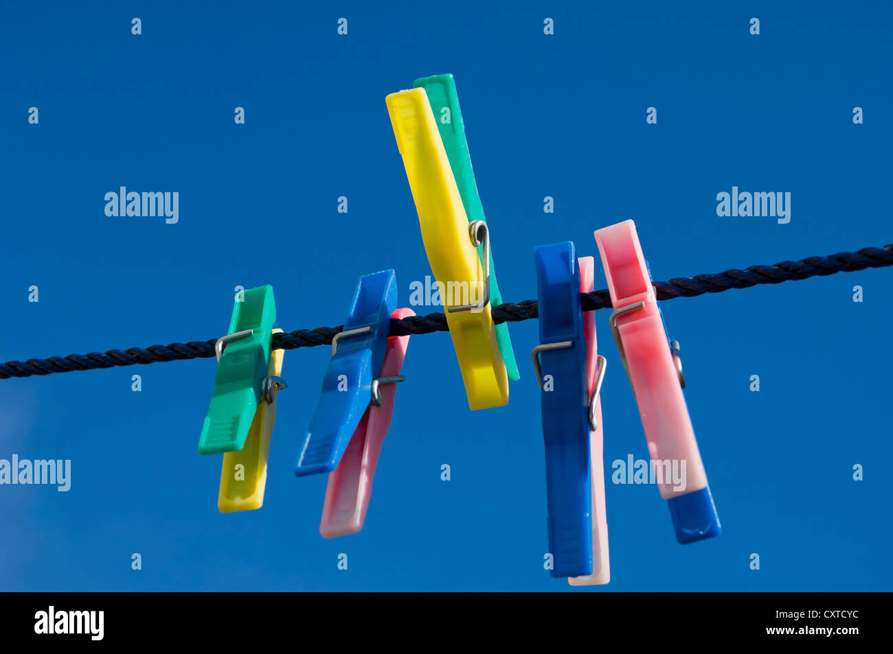 Close up of plastic clothes pegs peg on washing line with blue sky