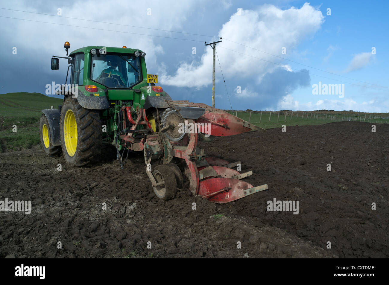 dh John Deere tractor TRACTORS UK Pulling plough ploughing fields farmland farming scotland pull plow soil Stock Photo