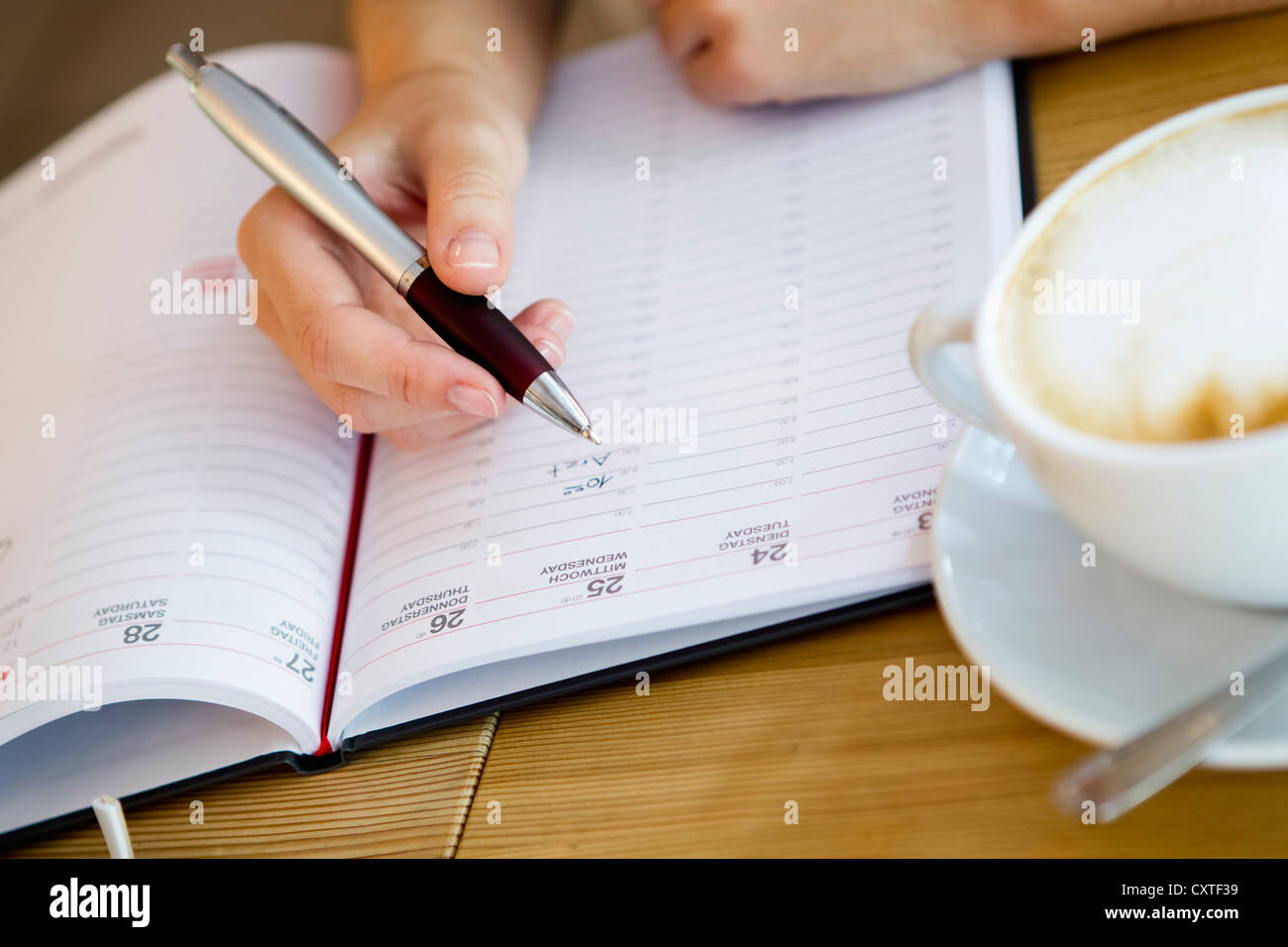 Close up of woman writing in planner Stock Photo