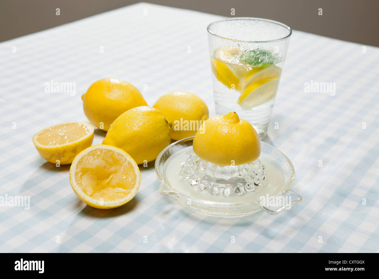 Lemons, juicer and glass of water Stock Photo