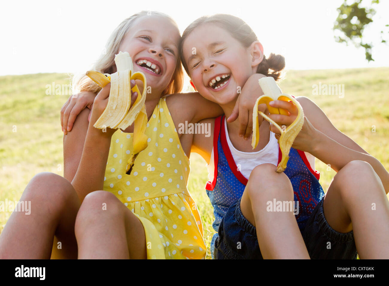 Laughing girls eating bananas outdoors Stock Photo Alamy