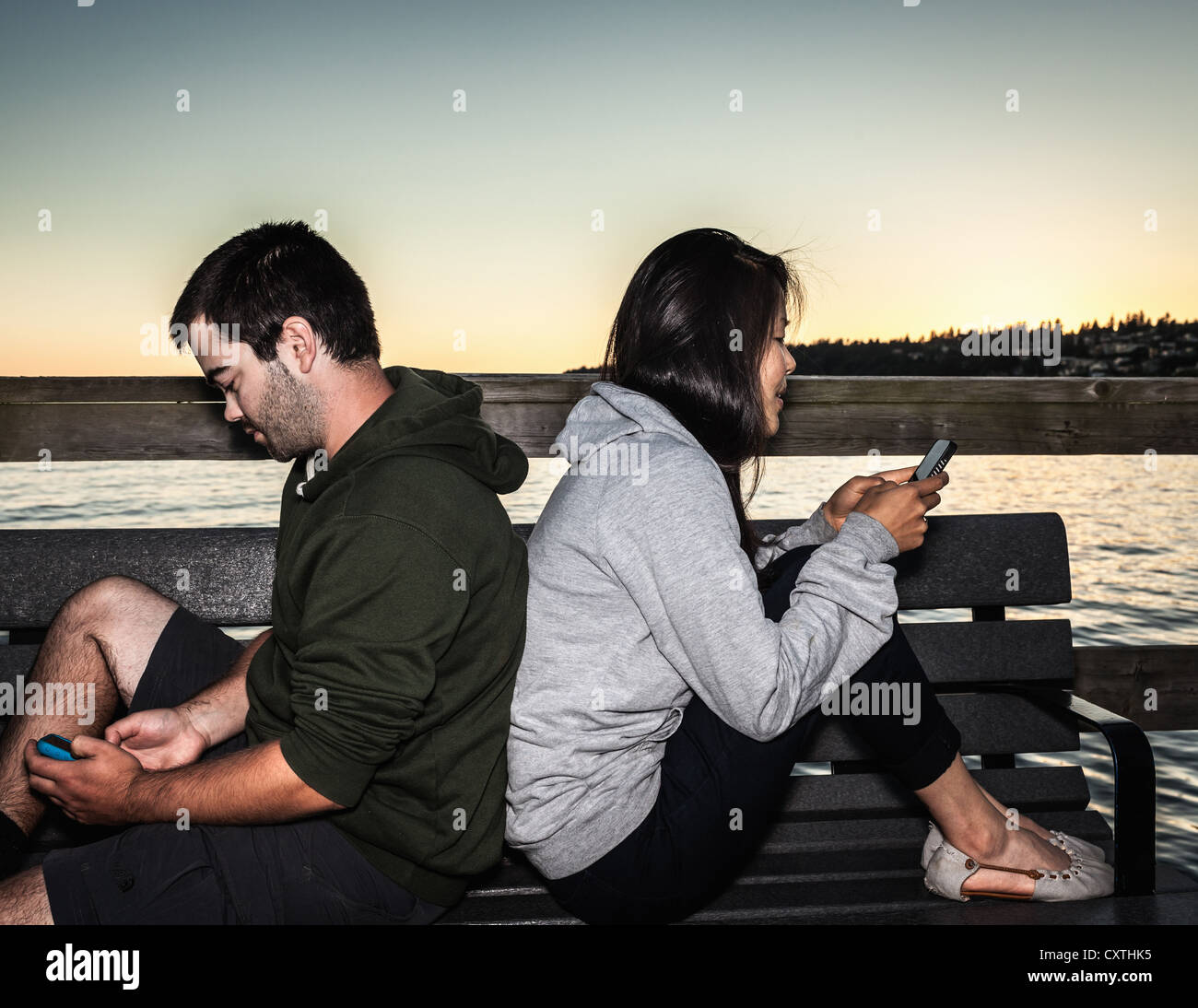 Couple using cell phones outdoors Stock Photo