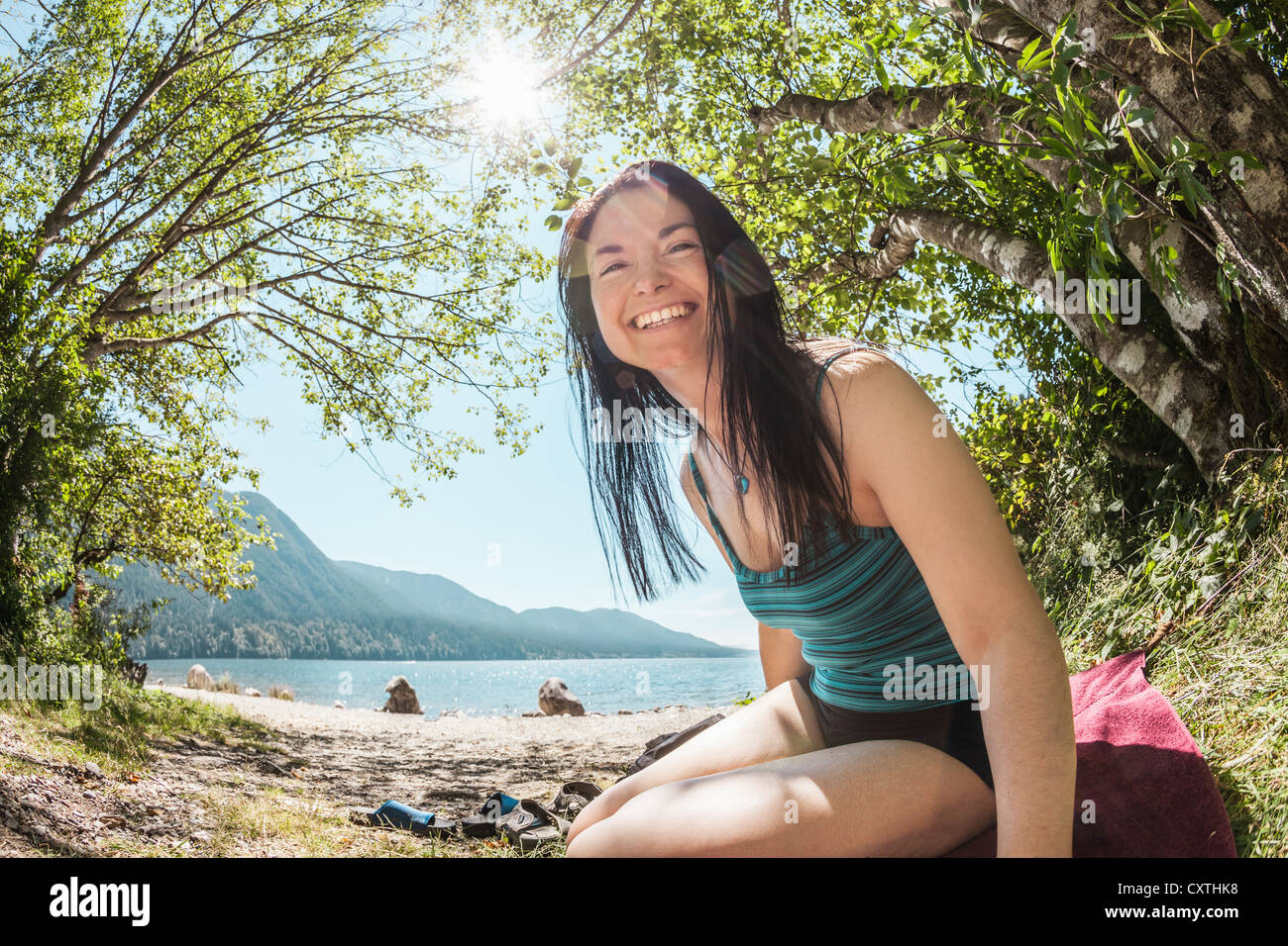 Smiling woman sitting by rural lake Stock Photo