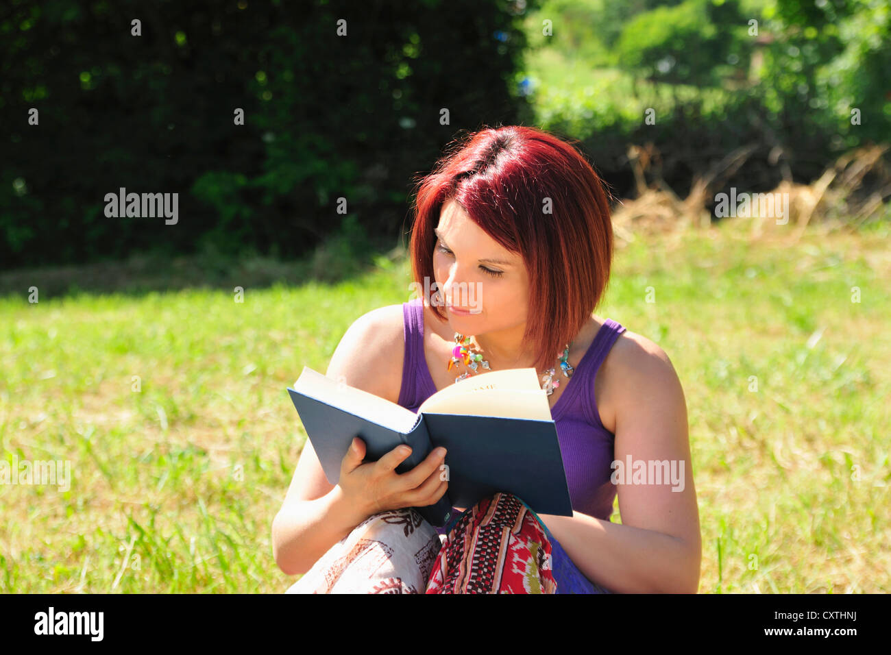 Woman reading book in grass Stock Photo