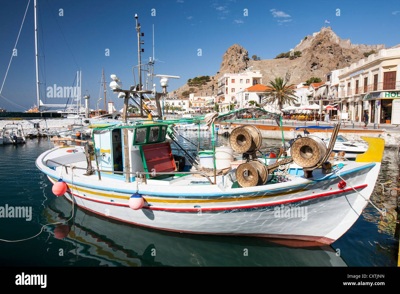 Traditional Greek fishing boats in Myrina on Lemnos, Greece, looking up towards Myrina Castle