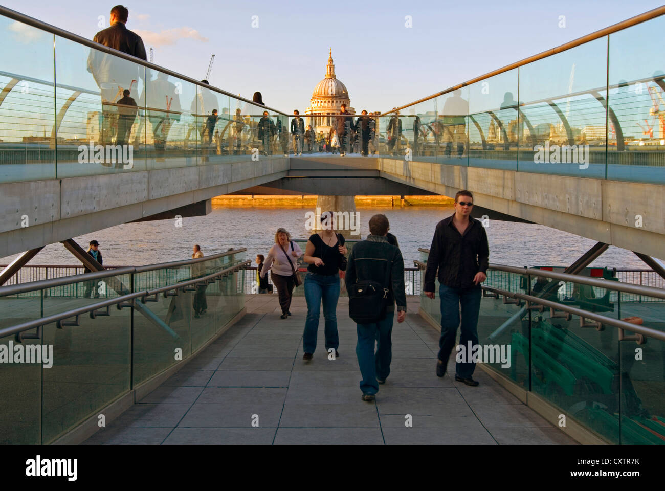 Horizontal split level view from the southern end of the Millennium Bridge with commuters & tourists crossing in the evening sun. Stock Photo