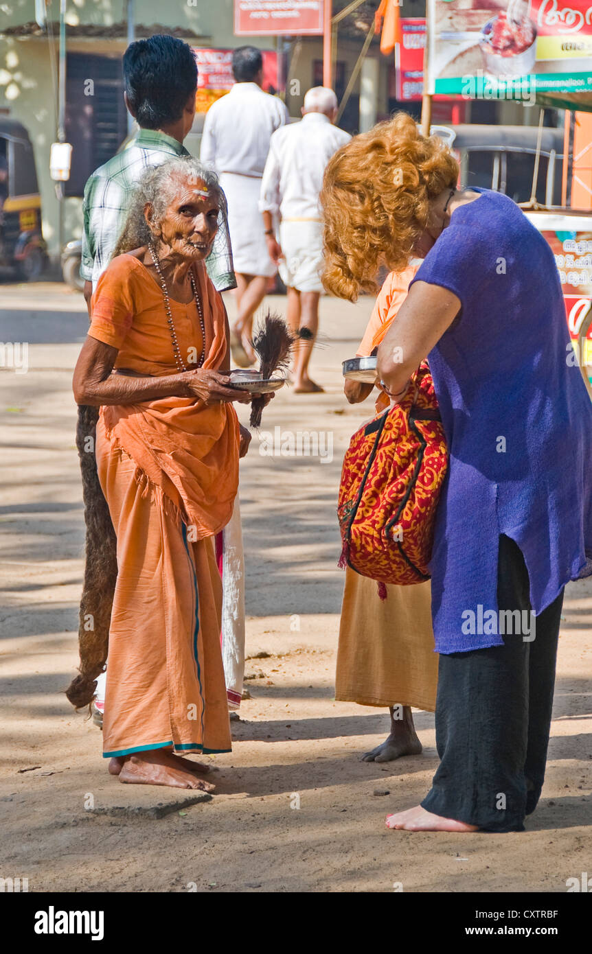 Vertical portrait of a female pilgrim begging for money from a tourist outside the Mannarasala Sree Nagaraja Temple in Haripad Stock Photo