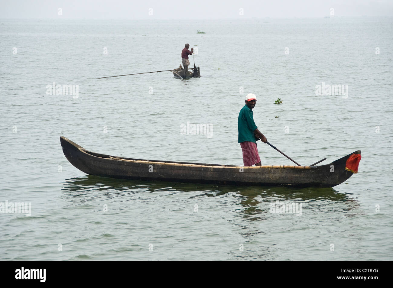 Horizontal view of traditional fishermen in their fishing boats out on the backwaters of Kerala, fishing for mussels. Stock Photo