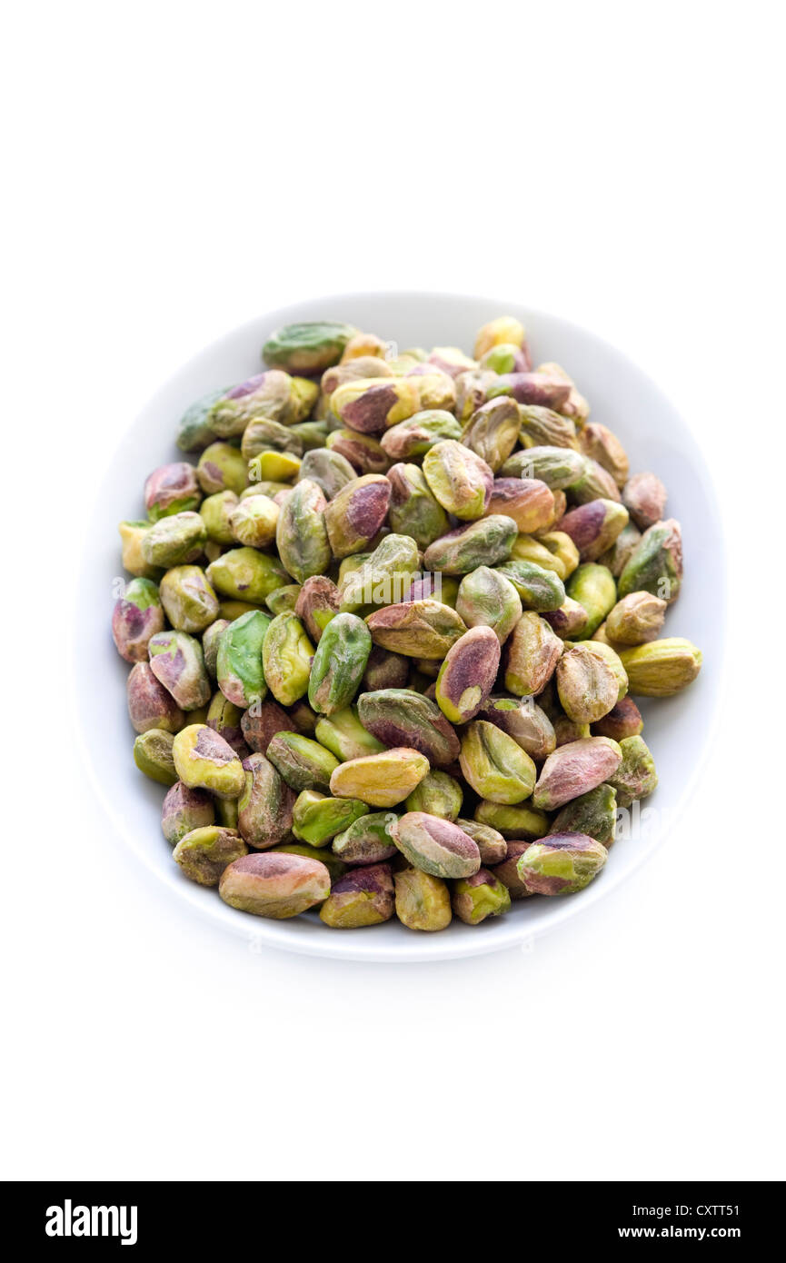 whole shelled pistachio nuts in a bowl isolated on a white background Stock Photo