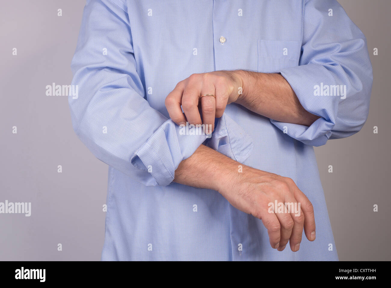 man who rolls up his shirt sleeves Stock Photo