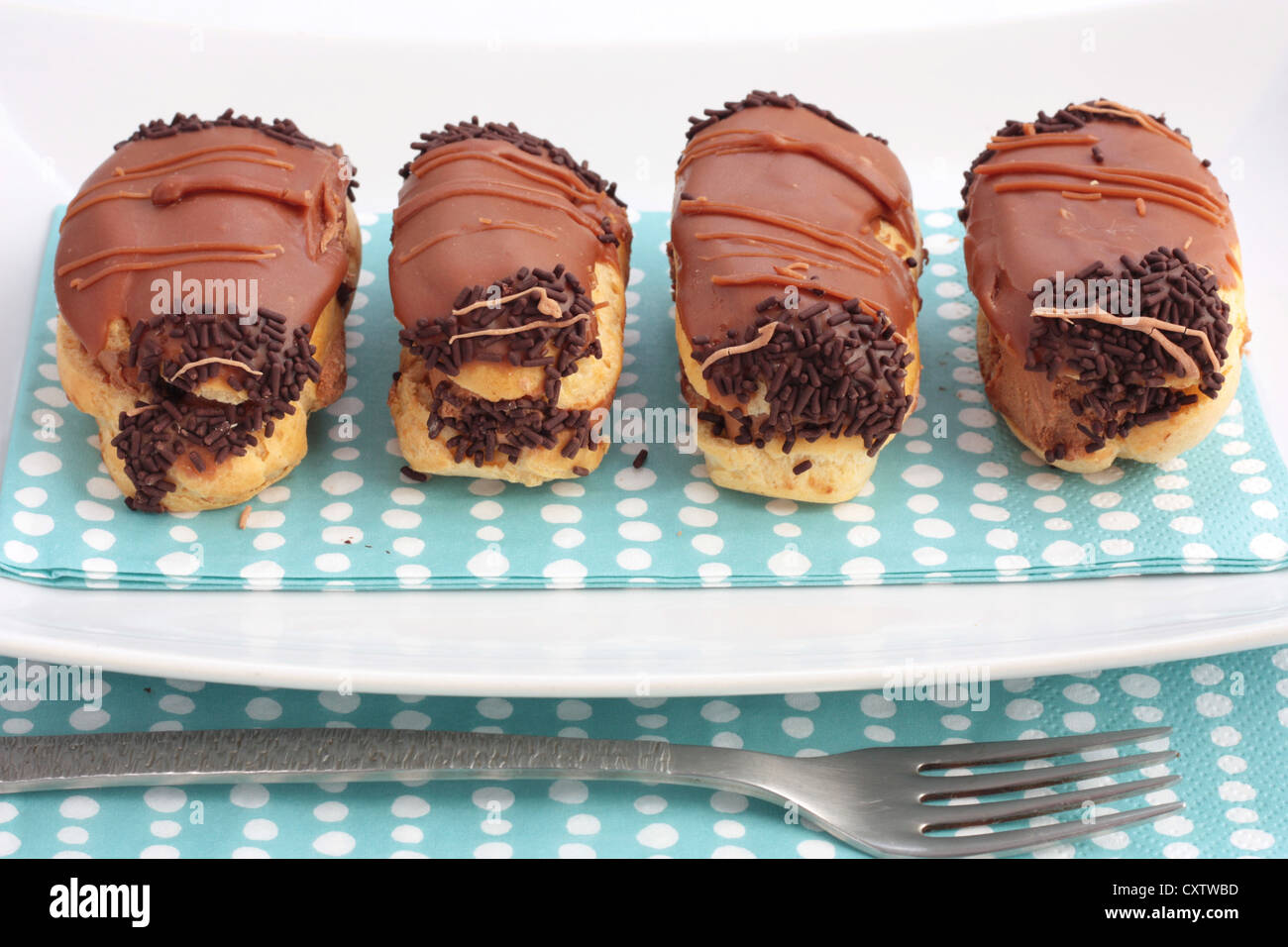 A plate of chocolate eclairs or choux pastry filled with chocolate cream and covered in chocolate icing. Stock Photo