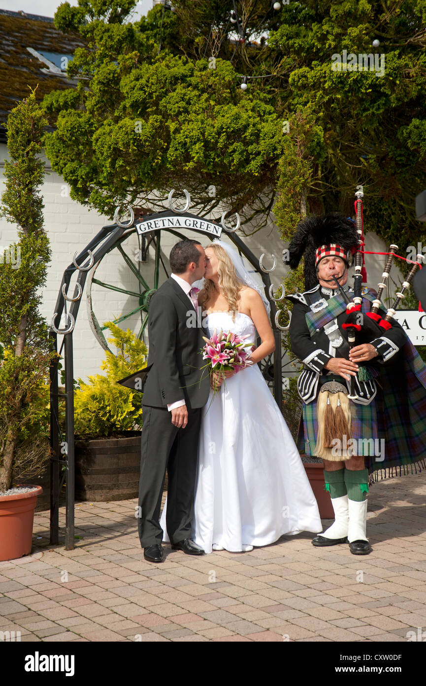 A Piper at Gretna leads the Newlyweds to the Photogenic Arch for pictures to be taken.  SCO 8654 Stock Photo