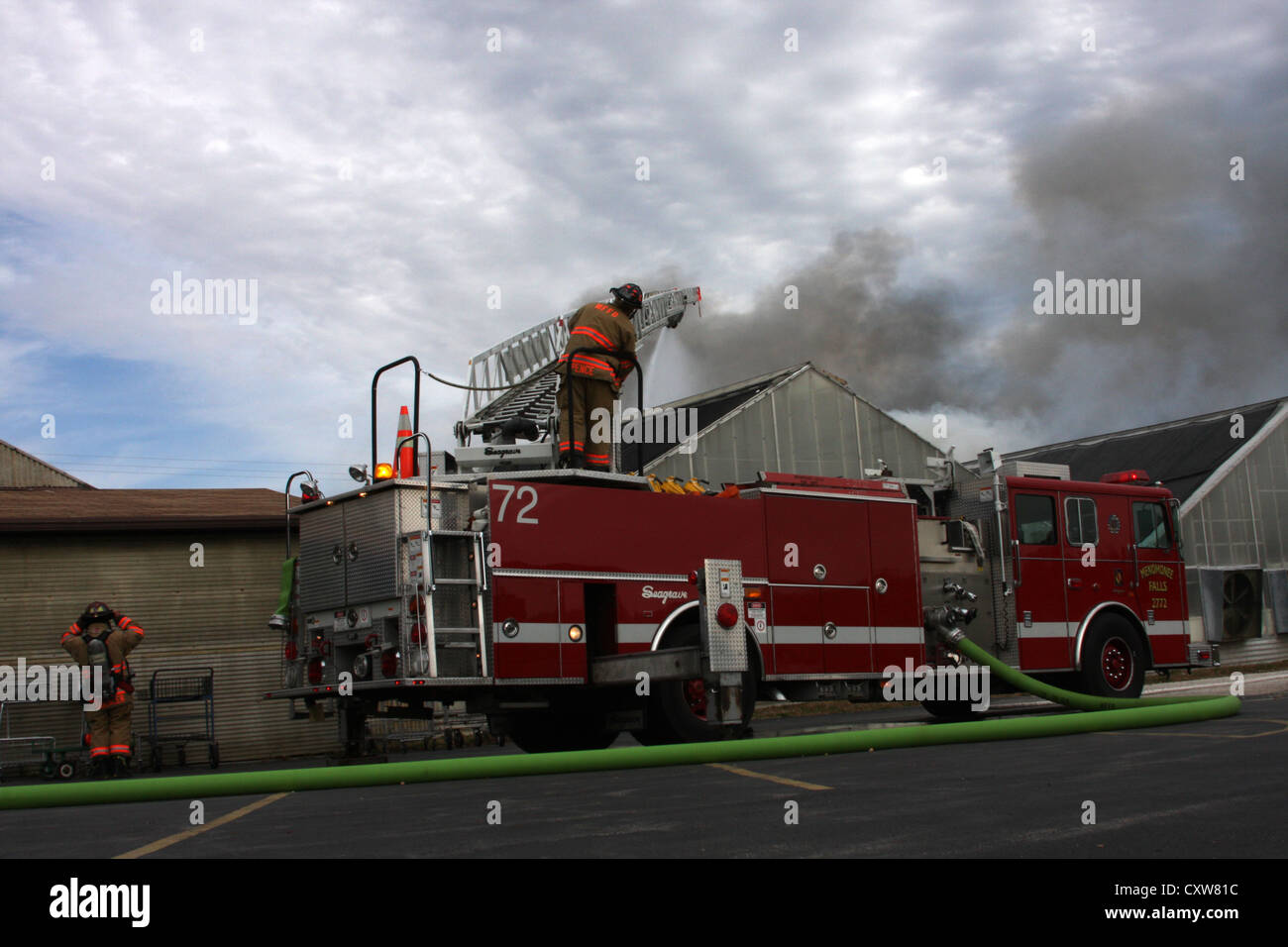 Fire ladder truck spraying wter on a fire in a greenhouse at a nursery
