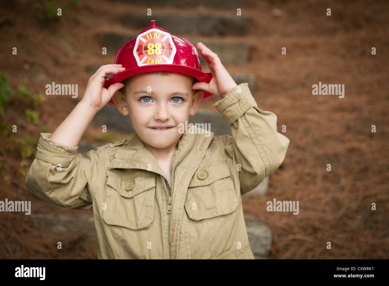 Happy Adorable Child Boy with Fireman Hat Playing Outside. Stock Photo