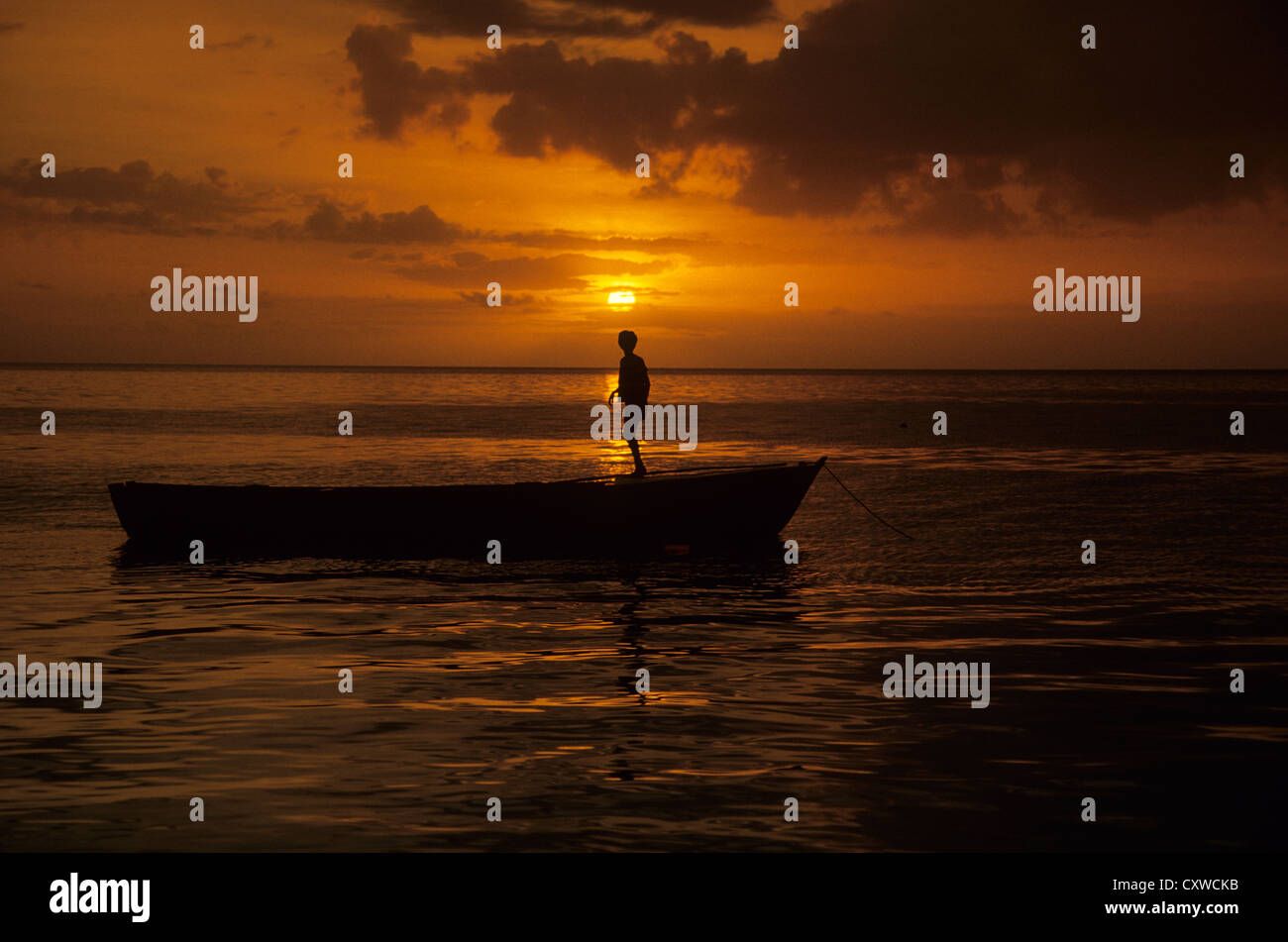 Fiji, sunset with boy on boat in silhouette. Stock Photo