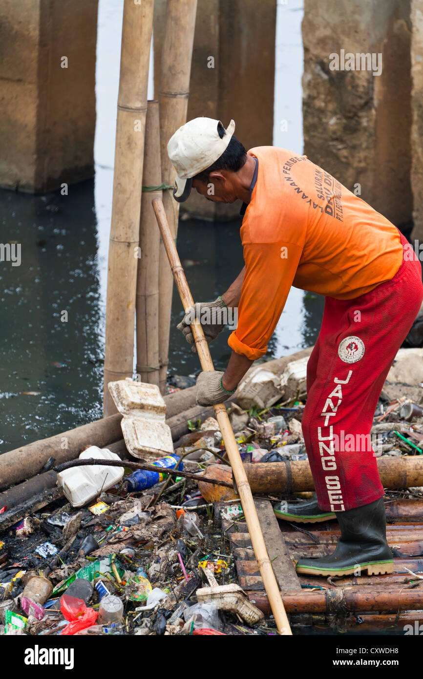 Worker cleaning a Canal in Jakarta, Indonesia Stock Photo