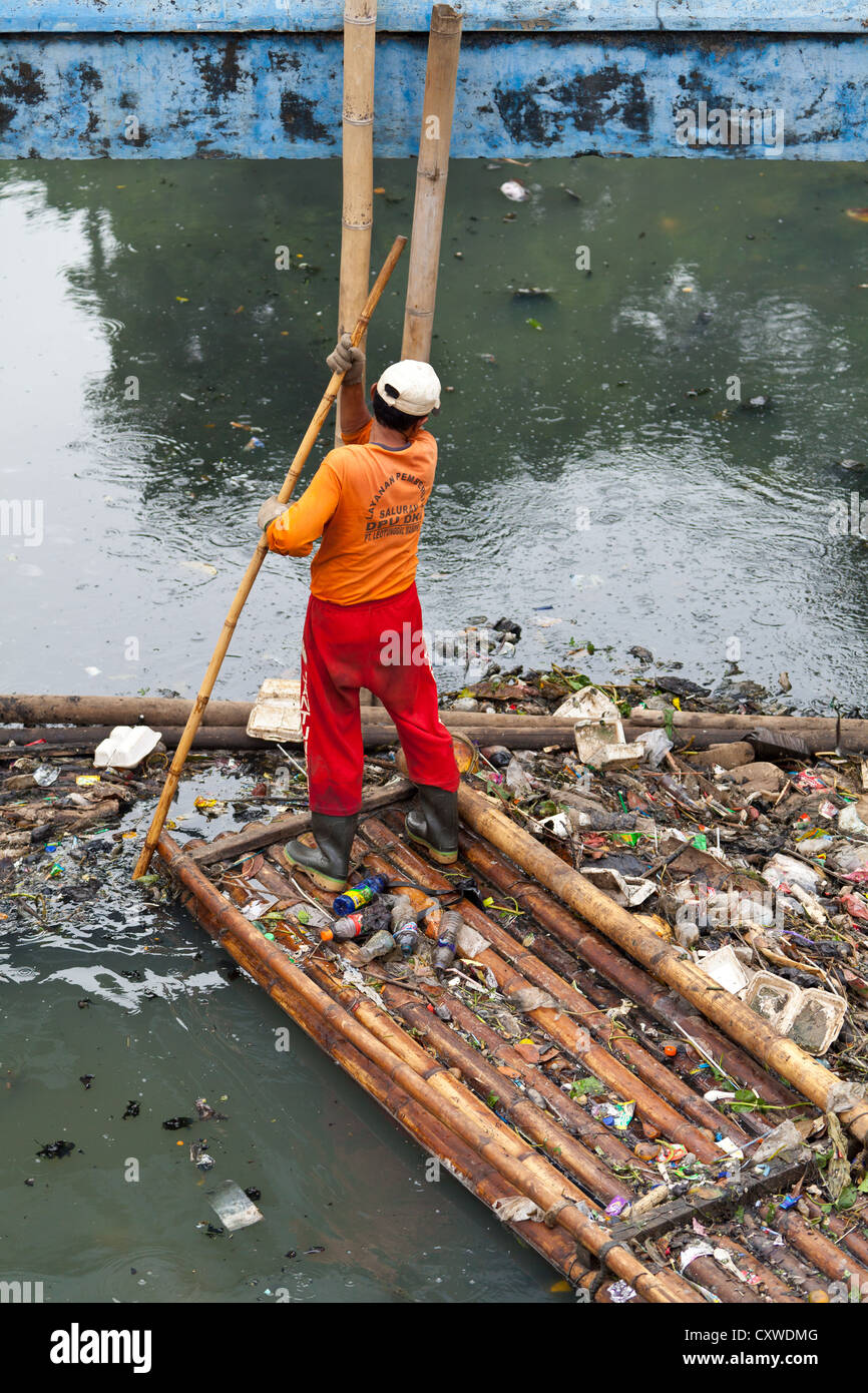 Worker cleaning a Canal in Jakarta, Indonesia Stock Photo