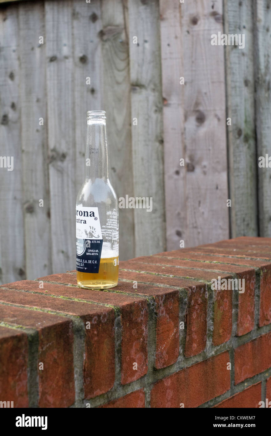 Part empty bottle left on top of a brick wall Stock Photo