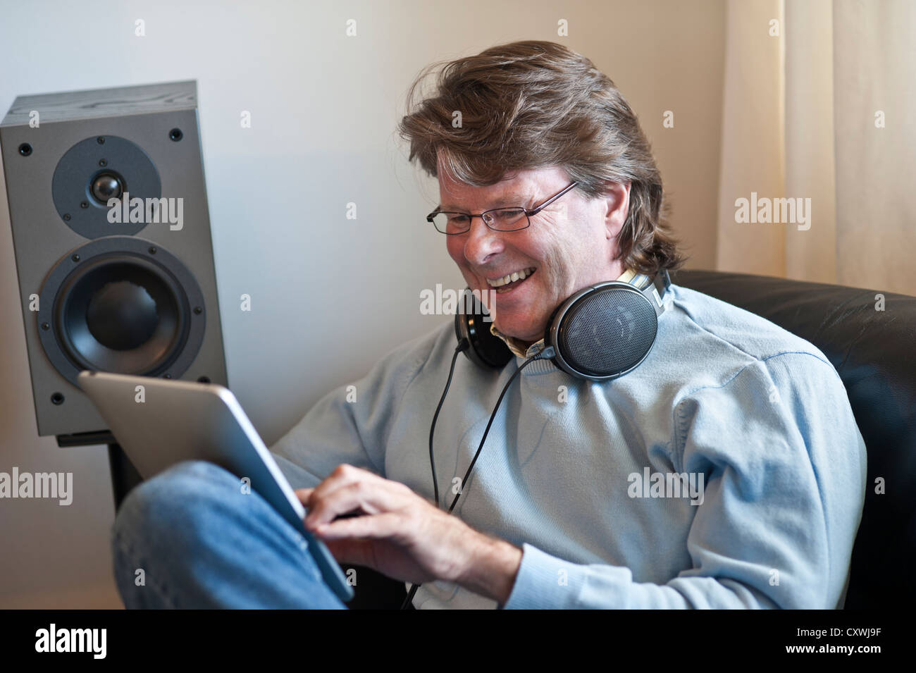 Mature man at home using his iPad tablet computer in contemporary living room Stock Photo