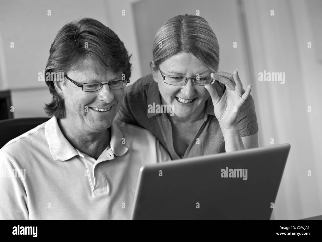 Attractive couple at home using their laptop computer together, in light contemporary living room office (B&W) Stock Photo