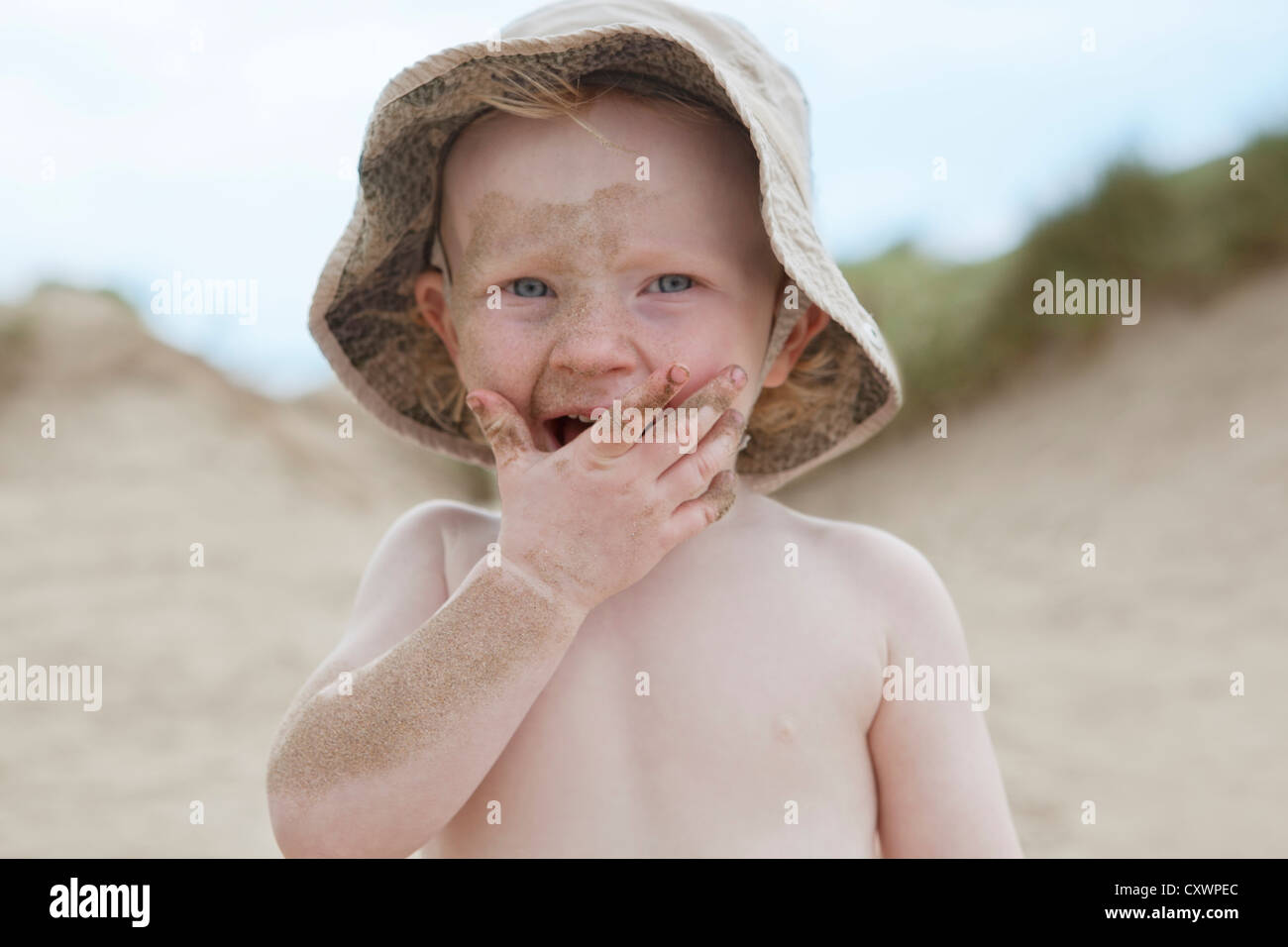 Boy covered in sand on beach Stock Photo