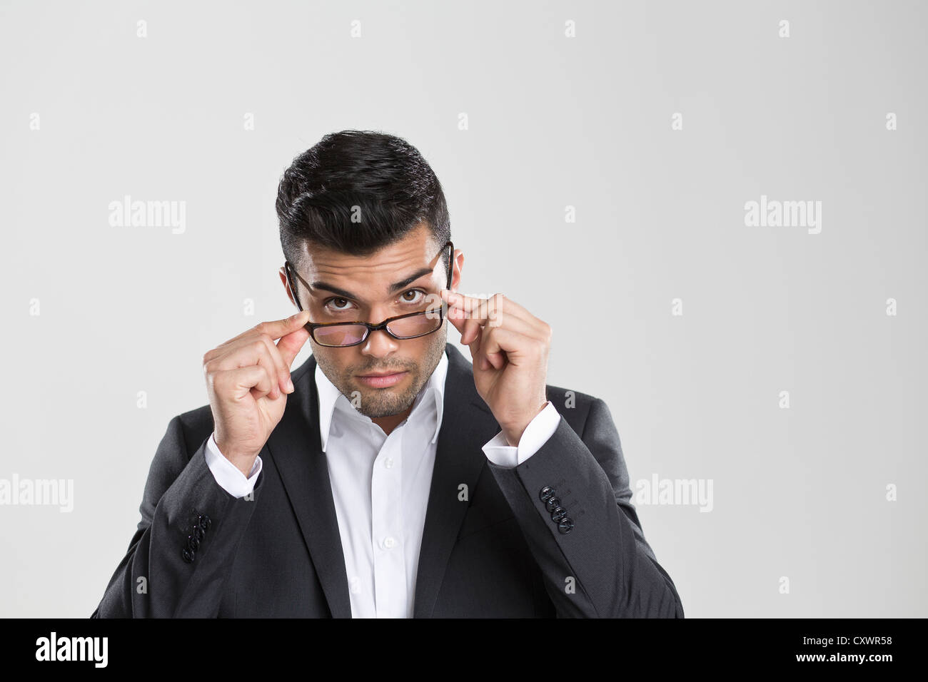 Businessman peering over glasses Stock Photo