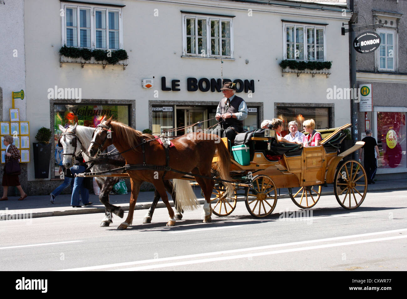 Sightseers enjoy a tour through the old town of Salzburg in a horse drawn carriage / fiaker, Stock Photo