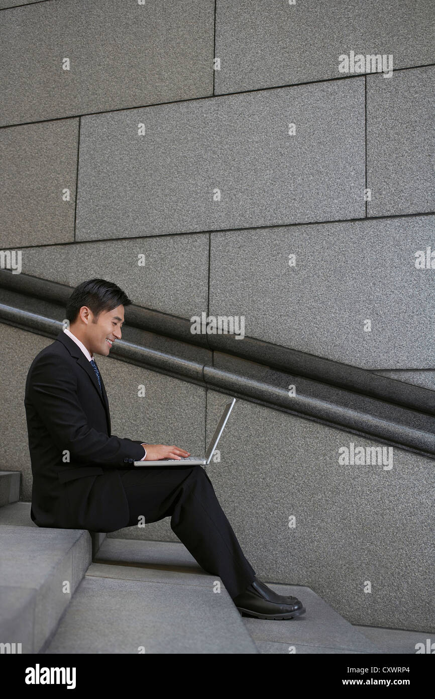 Businessman using laptop on city steps Stock Photo