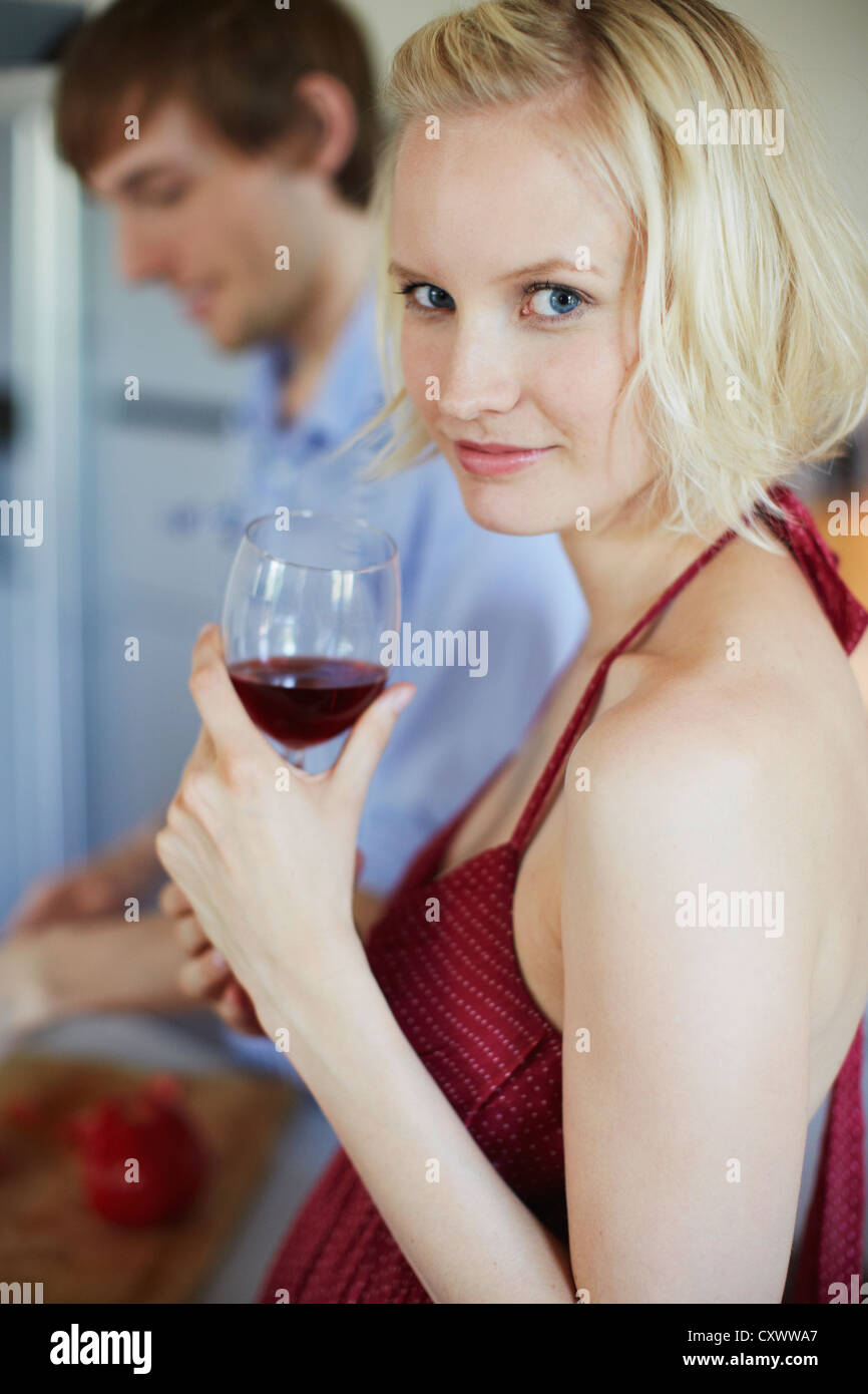Smiling woman drinking wine in kitchen Stock Photo