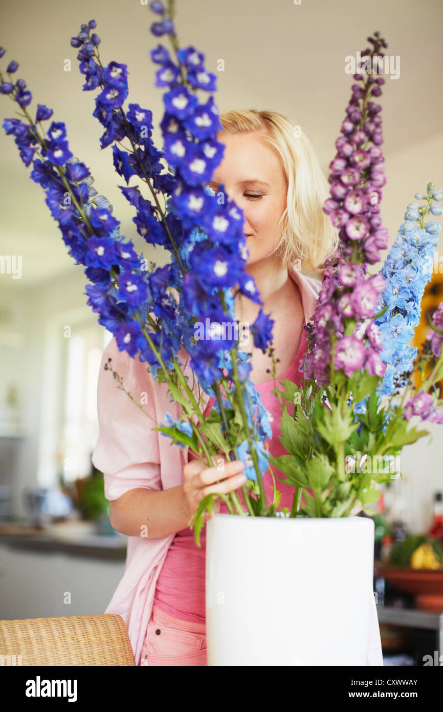 Woman arranging flowers in kitchen Stock Photo