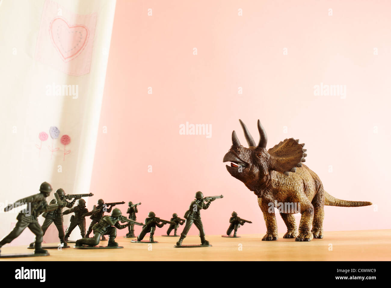 Toy soldiers attacking dinosaur Stock Photo