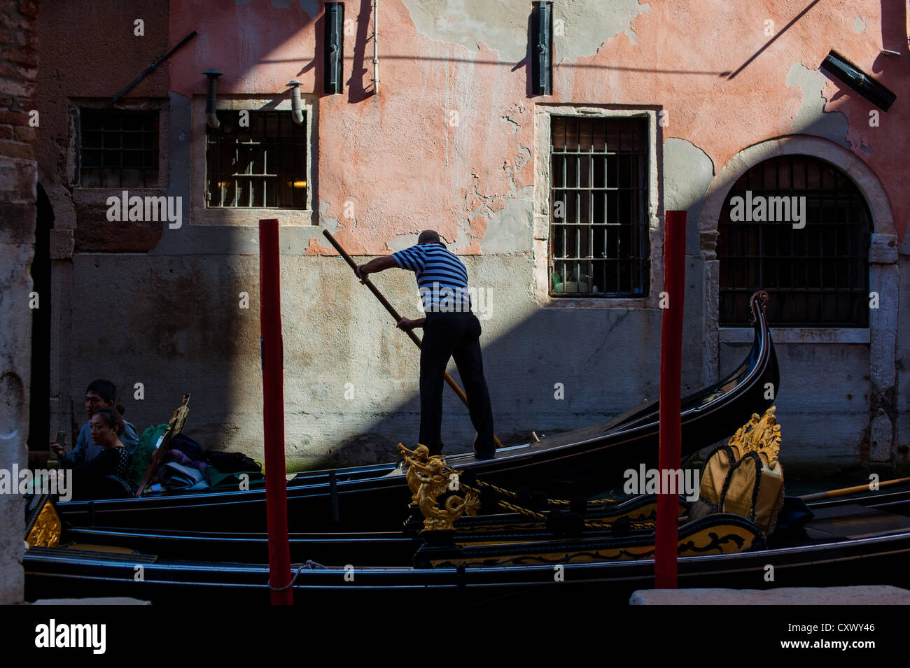 Silhouette of gondolier in front of venetian building wall Stock Photo