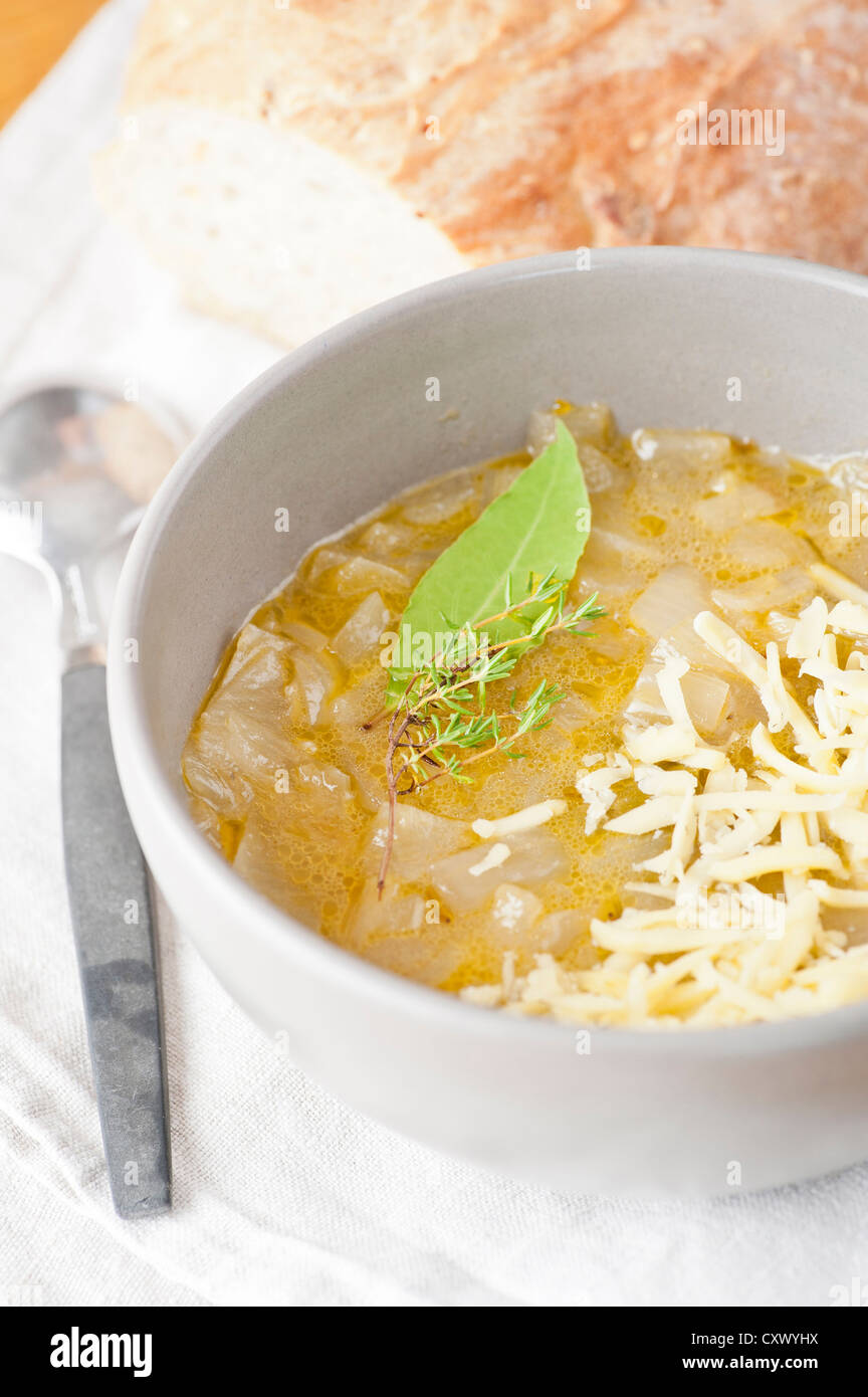 Closeup of hot onion soup with grated cheese, thyme and bay leaf, served with freshly baked bread Stock Photo