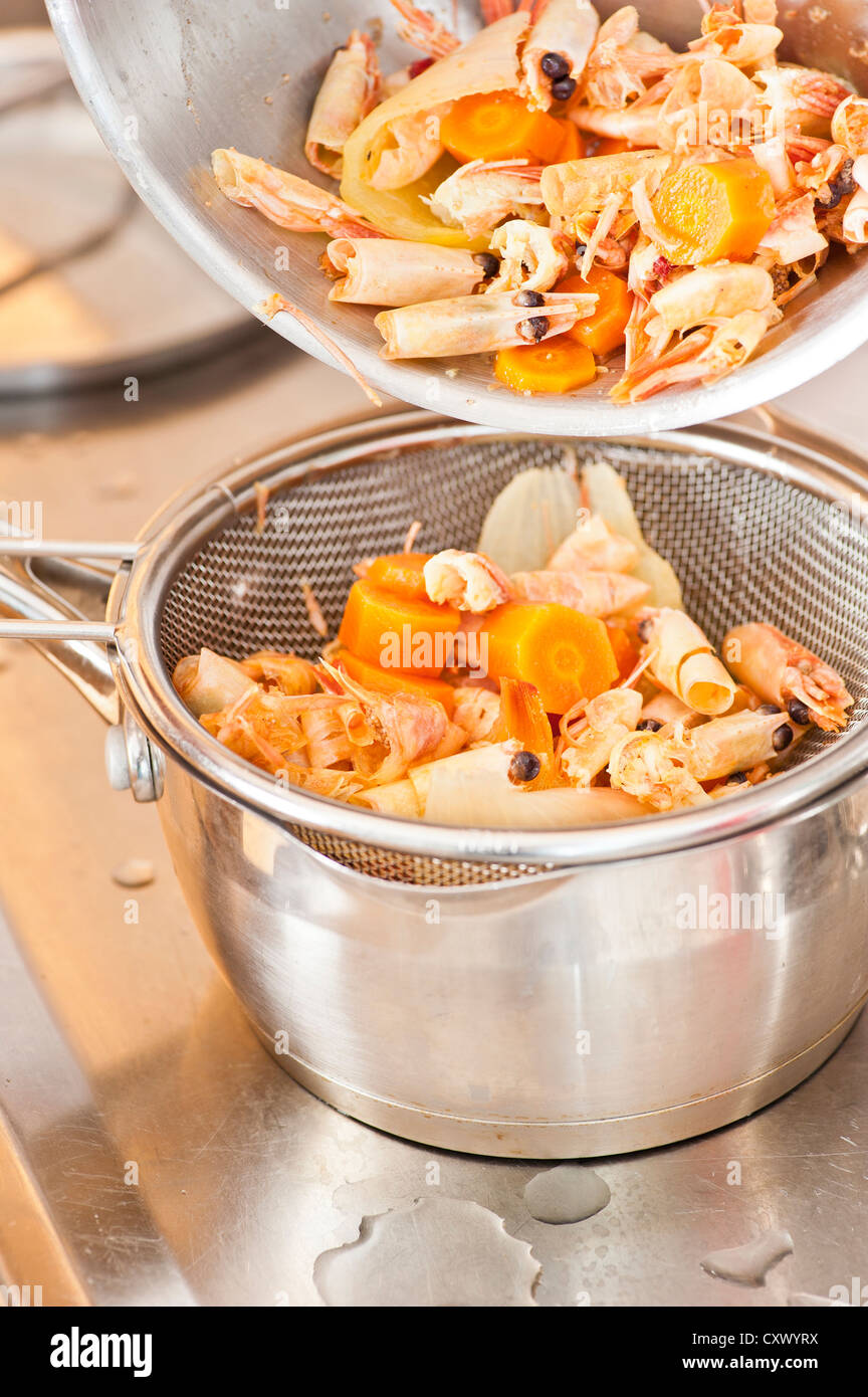 Sifting of boiled prawns, onions and carrots with sieve and pots Stock Photo