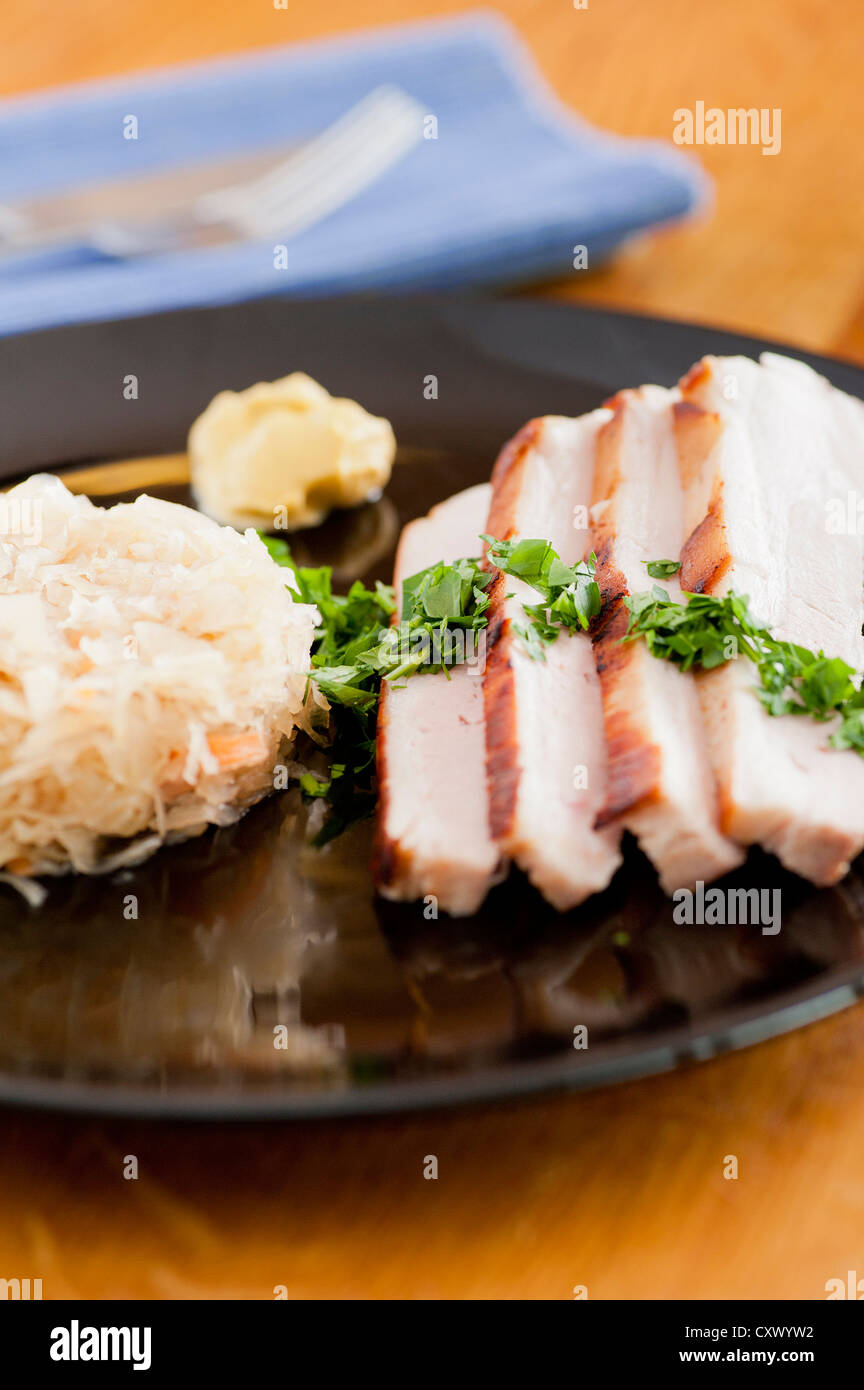 Traditional german food, roasted pork with sauerkraut. Served with mustard and parsley Stock Photo