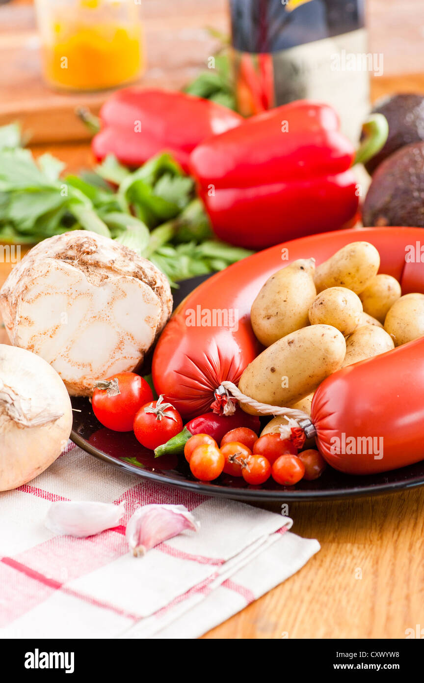 Counter in kitchen with sausage, garlic, tomatoes, potatoes, chili pepper and other ingredients for cooking Stock Photo