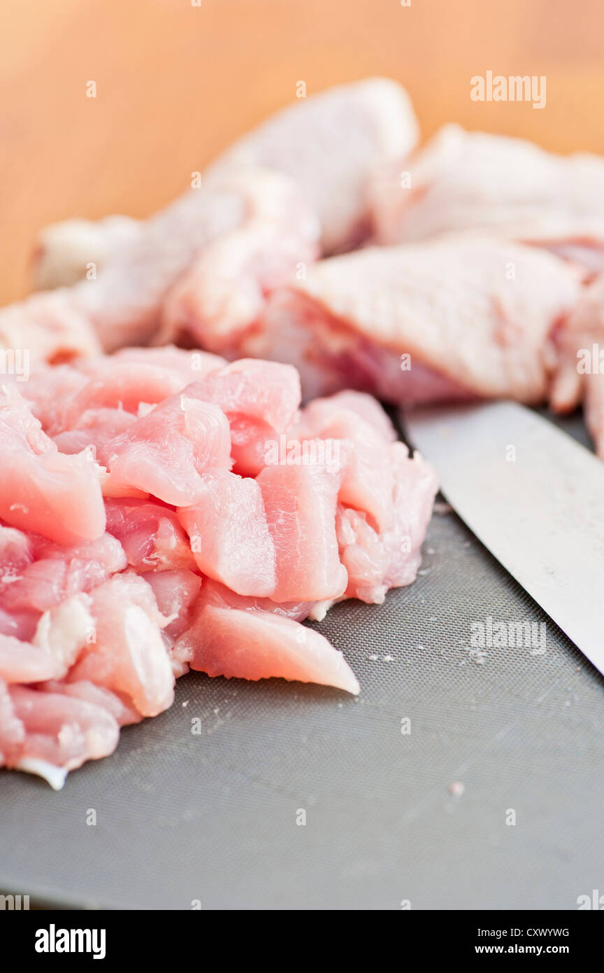 Cut up pieces of uncooked chicken on a plastic cutting board Stock Photo