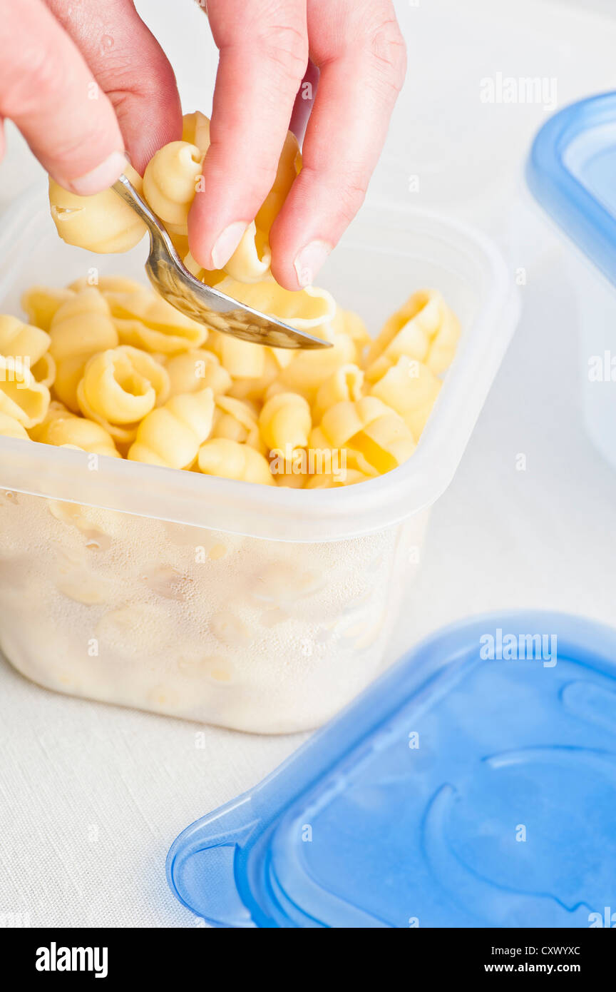 Closeup of plastic box being filled with cooked pasta Stock Photo