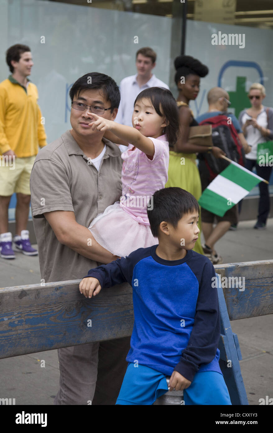 Chinese father and 2 children watch the Nigerian Independence Day Parade on 3rd Ave in NYC. Stock Photo