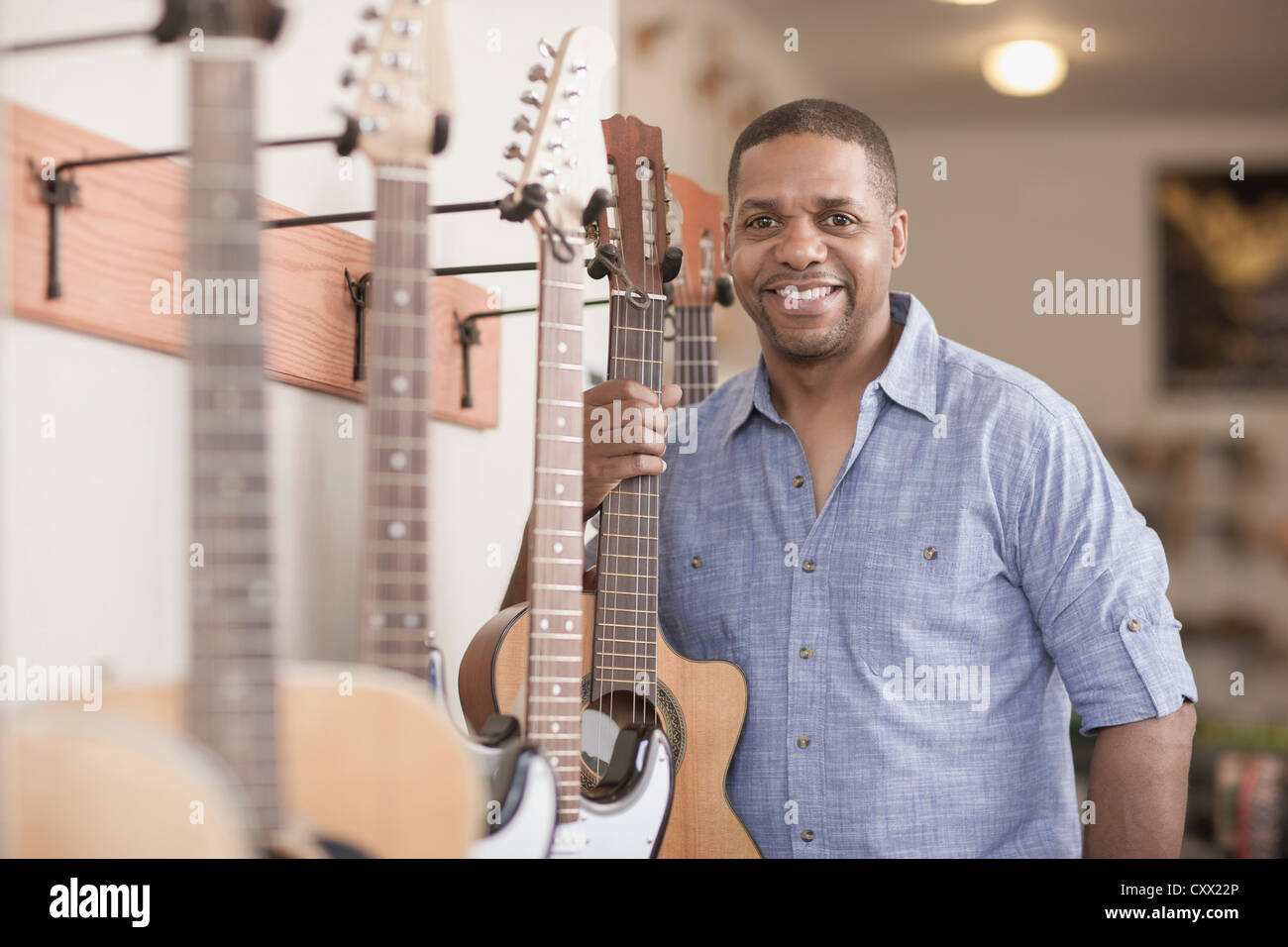 Native American man holding guitar in music store Stock Photo