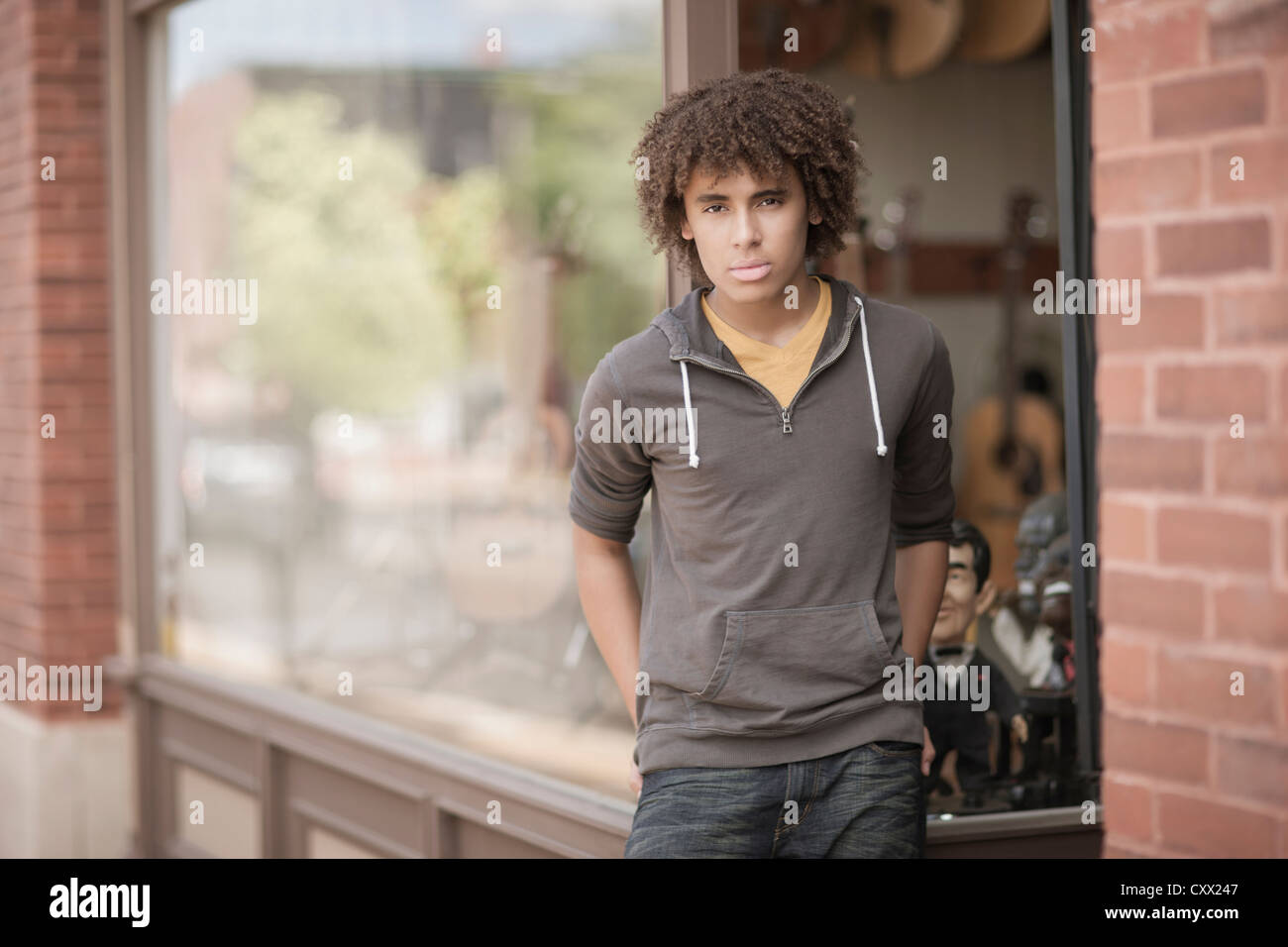 Mixed race teenager standing outside music store Stock Photo