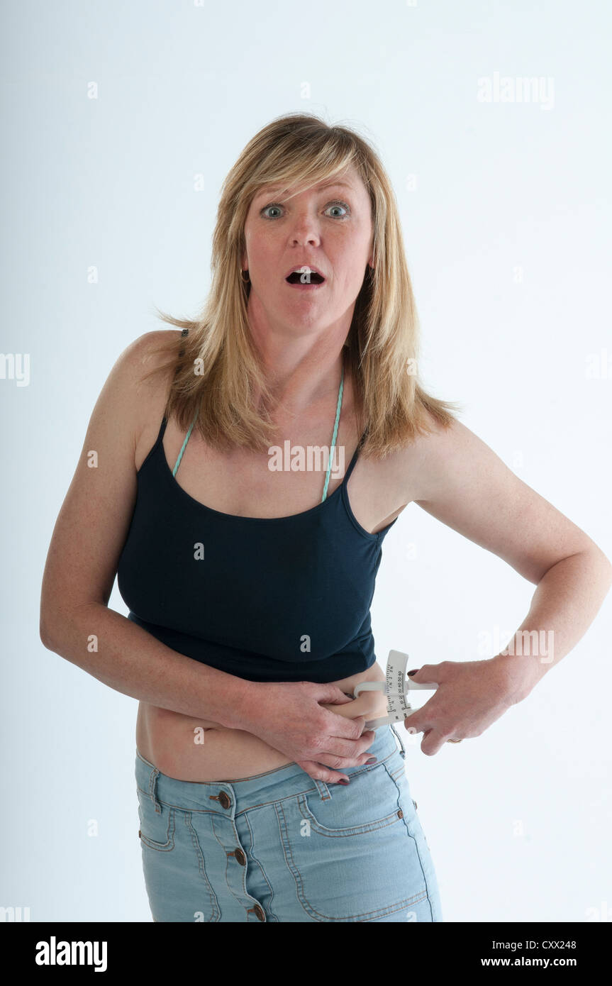 Woman with shocked expression looking at body fat caliper measurement