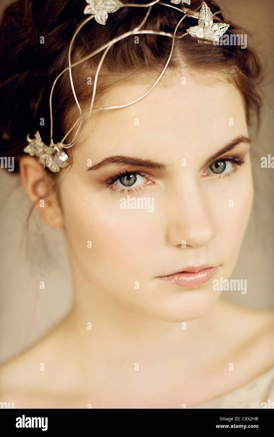 Close portrait of young woman with silver headpiece and braided hair looking into the camera Stock Photo