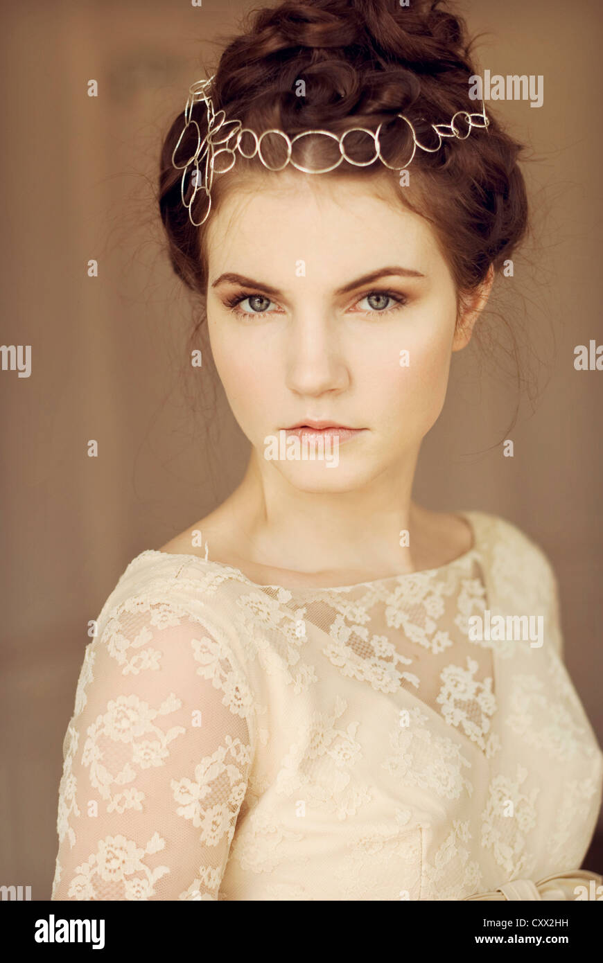 Portrait of young woman with sterling silver headpiece and white lace dress looking straight forward Stock Photo