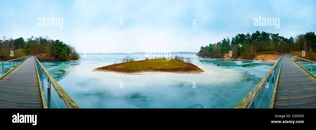 Panoramic photo of a frozen blue lake with a bridge. Stock Photo