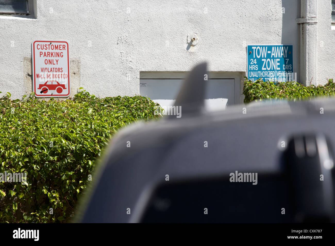 car parked in front of customer parking only and towaway zone signs